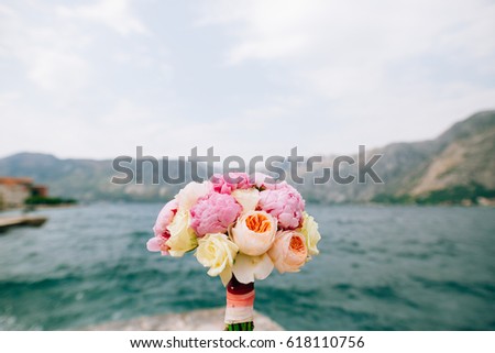 Bridal bouquet of roses and peonies on the background of water. Bay of Kotor, Montenegro.