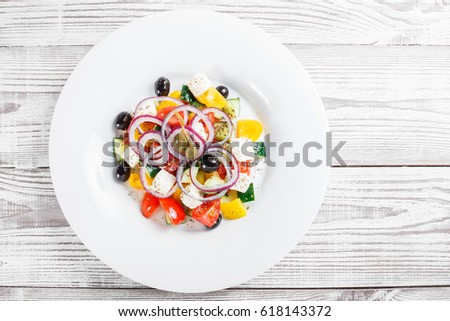 Greek salad with fresh vegetables, olives and feta cheese on wooden background close up. Top view