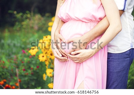 Image of pregnant couple. Husband touching his wife belly with hands. outdoor. summer.