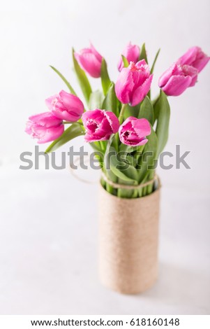 Pink tulips on a light background in handmade vase. 