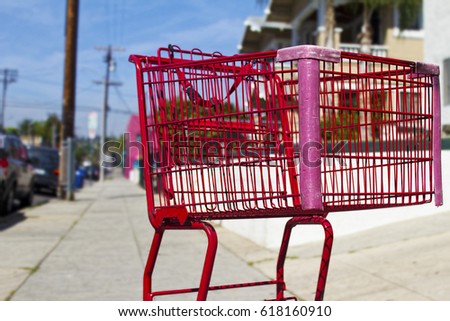 Bright Red Grocery Shopping Cart on Sidewalk in Daytime