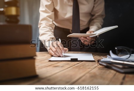 Business lawyer working hard at office desk workplace with book and documents.