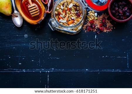 Jar of tasty homemade oatmeal granola with fruits and nuts on dark vintage background. Top view. Flat lay style. Clean eating, vegan, vegetarian, detox and dieting concept