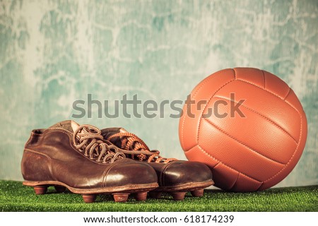 Retro outdated soccer spike boots and football. Vintage old style filtered photo