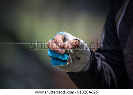 Angler tying a fishing hook to rubber worm lure