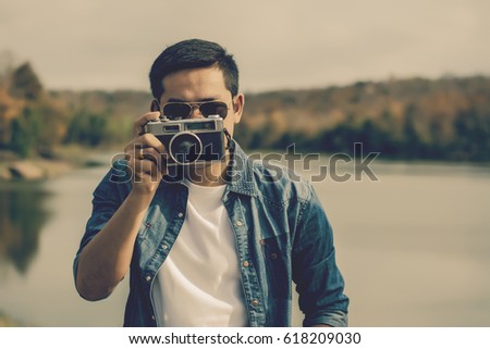Young man tourist  standing and taking photos with vintage camera.