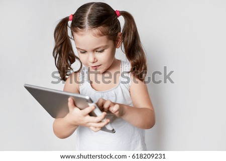 Little girl is playing a tablet