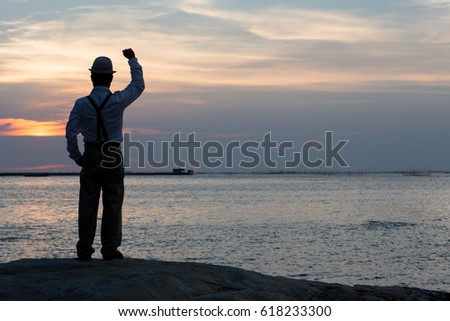 Man raised arms on the beach under sunset twilight time, beautiful seascape evening with a man shadow , silhouette light. Win and freedom concept.