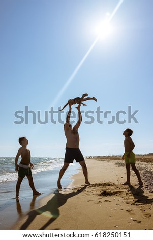 Father and man playing on the sand beach throwing in the air flying