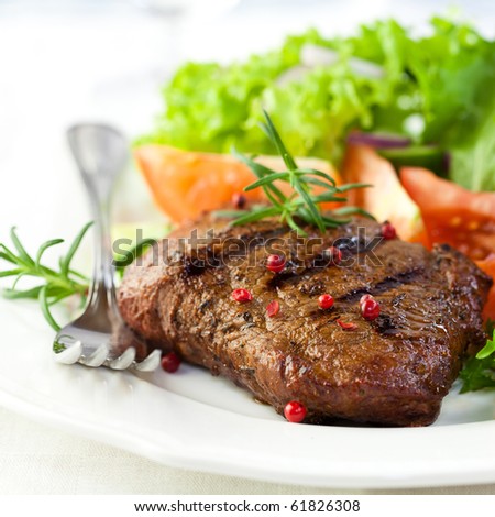 Grilled steak with green and red lettuce, tomatoes, cucumber, red onion, pink pepper and fresh rosemary. Home made tasty food. Concept for a tasty and healthy meal. White background. Close up. Royalty-Free Stock Photo #61826308