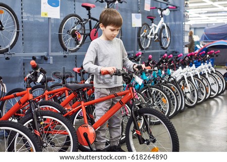Boy chooses a bicycle in a sports supermarket