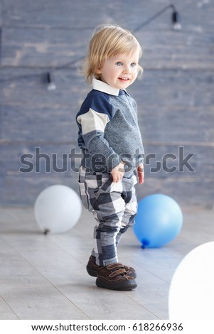 Cute baby boy celebrating birth day with air balloons. Scene of kid with presents and blue balloons.