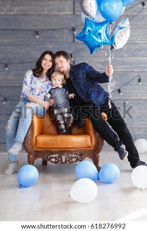 Portrait of happy mother, father and son on his second birthday party indoors. Happy birthday, joyful and laughing two years old baby boy. Young Stylish happy family concept.