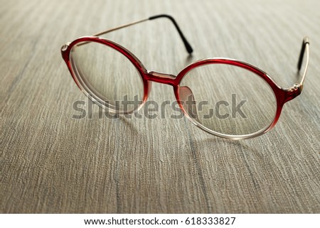 red eye glasses put on wood table with window light