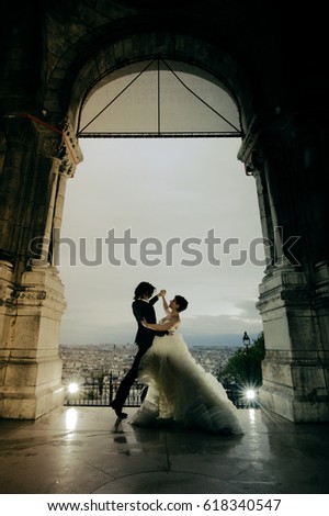 A young couple just married, wearing stylish clothes, posing and dancing for wedding photos, in a charming location in Paris