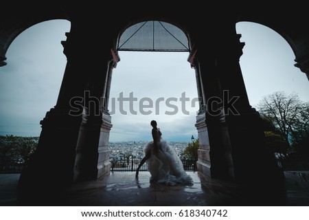 An attractive young woman just married, wearing a stylish white dress, posing and dancing for the wedding pictures, in a charming location in Paris
