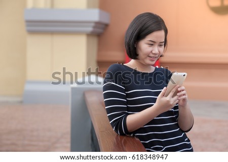 Weekend lifestyle scene of adult Asian woman using mobile phone. Urban lifestyle on weekend with technology.