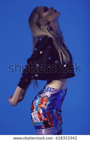 Model posing in short black top and multi skirt on blue background