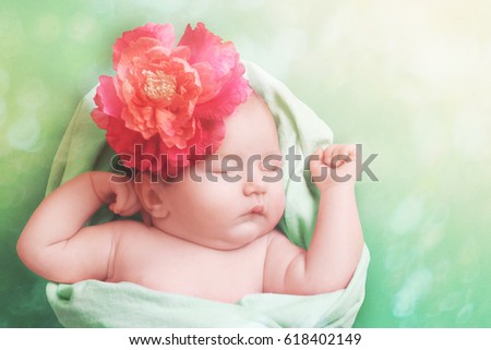 Adorable baby girl sleeping on green blanket. Spring portrait girl with flower decoration