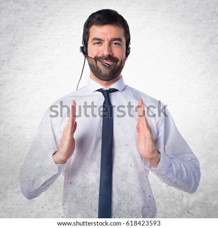 Handsome telemarketer man holding something on textured background