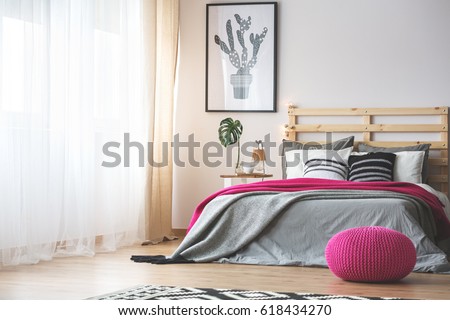 King-size bed in bright bedroom with pink accessories Royalty-Free Stock Photo #618434270