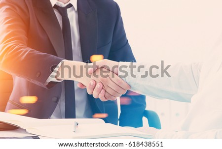 Close up of two business partners shaking hands at a table. Concept of a negotiation going well. Toned image