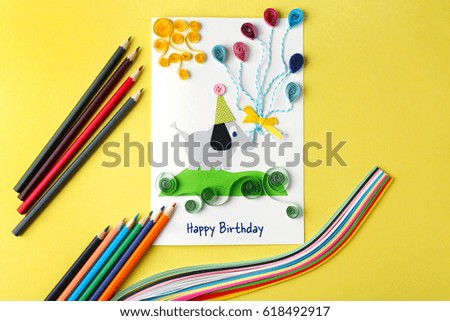 Handmade gift card and colorful crayons on yellow background
