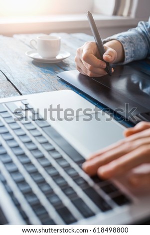 Person using stylus on graphic tablet with computer
