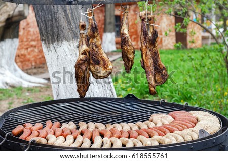 Sausages and pork ham are roasted on the grill in the open air. Sausages are traditionally prepared at all gastronomic festivals. Very hearty and tasty dish. Street picture of food.