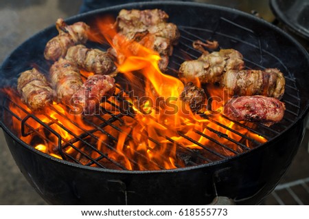 Sausages in bacon are roasted on the grill in the open air. Sausages are traditionally prepared at all gastronomic festivals. Very hearty and tasty dish. Street picture of food.