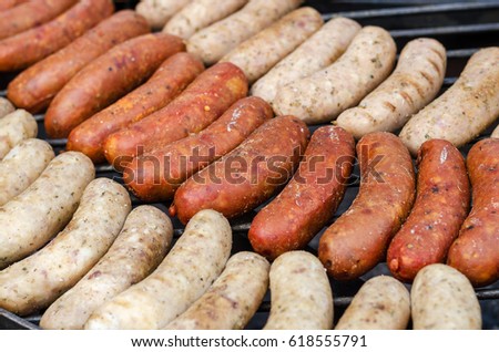 Sausages are roasted on the grill in the open air. Sausages are traditionally prepared at all gastronomic festivals. Very hearty and tasty dish. Street picture of food.