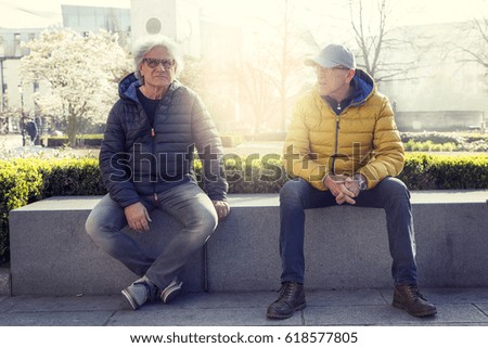 mature men friends enjoying vacation in a modern city - concept of active senior who travel and have fun