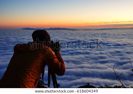 A man taking a photo at sunrise