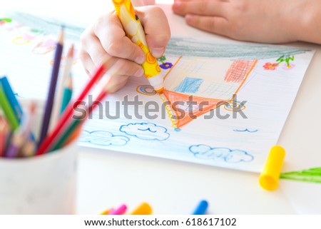 Children's hands behind drawing at a table