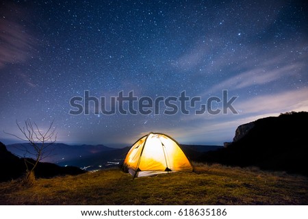 Glowing tent in the mountains under a starry sky Royalty-Free Stock Photo #618635186