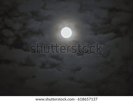 Soft shining full moon surrounded by moody fantasy-like clouds, night sky scene