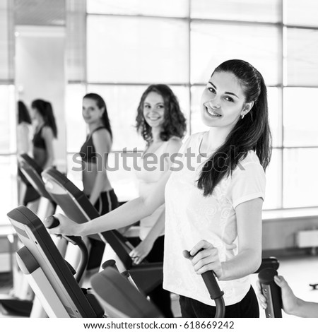 Young women running on treadmill in gym.