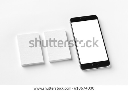Mockup of two blank vertical business cards and cell-phone isolated at white textured paper.