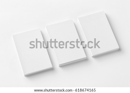 Mockup of three business cards stacks at white textured paper background.