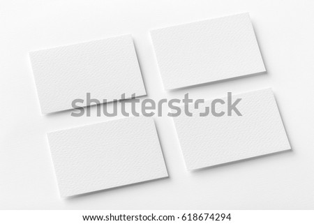 Mockup of four white business cards arranged in rows at white design paper background.