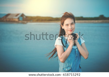 Beautifu woman holding  camera taking pictures looking at camera during summer holiday vacation travel at the ocean.