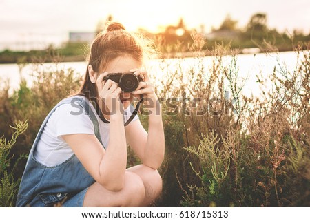 Beautiful girl is taking pictures in the meadow.