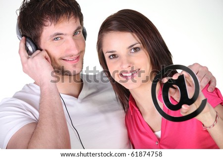 Young man and woman with headphones and at sign