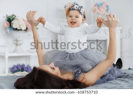 Mother with little cute daughter having fun indoor. smiling, kissing and hugging. sweet girls in beautiful dresses. 