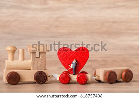 Miniature Couple Standing over Red Heart Shape with Wooden Toy Train on wooden background,Image to Valentine Day concept.