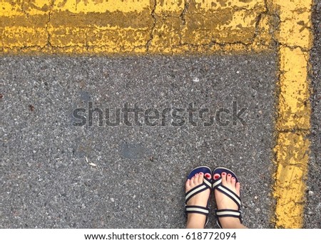 Asphalted street with yellow line and woman feet
