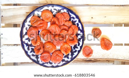 the dried fruit - dried apricots on the plate with Uzbek ornament and on wooden box