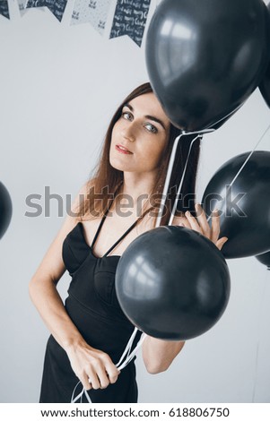 Young beautiful girl in a black dress with black balloons. Toning.
