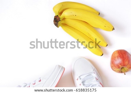White sneakers, red apple and a bunch of yellow bananas. Healthy lifestyle concept. Flat lay stock photography. Top view