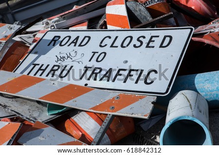 A dump of Road Closed Sign fell down on a road with broken barricades pile of metal and pipes close to construction zone. Miami. Florida. USA